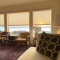 living room with white roller shades and sunset view over water