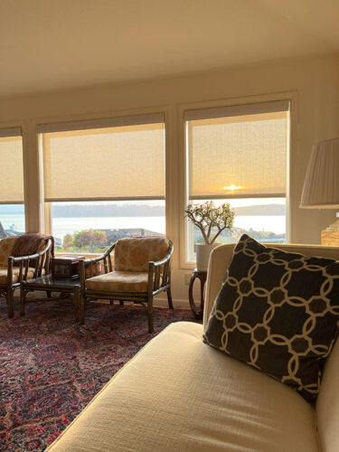 living room with white roller shades and sunset view over water